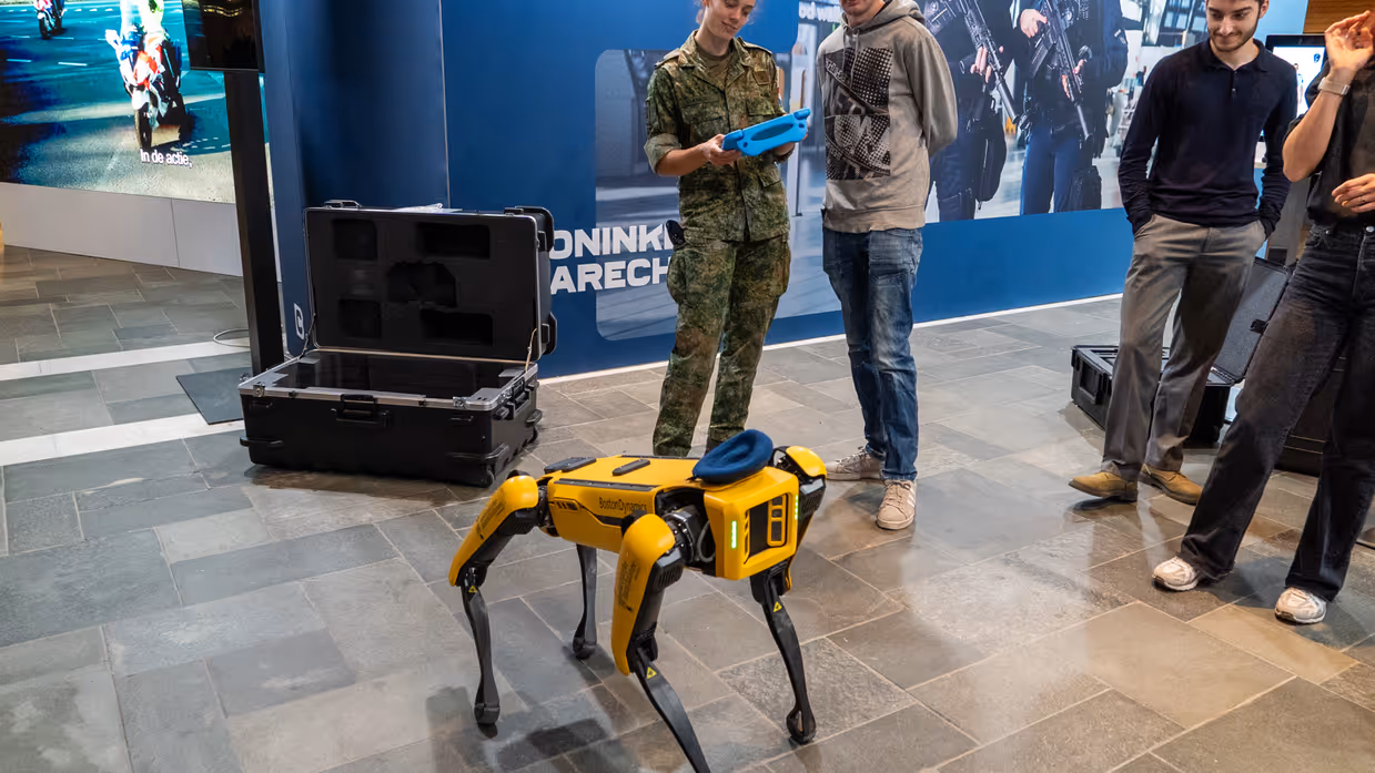 Bezoekers kijken naar een robothond. 