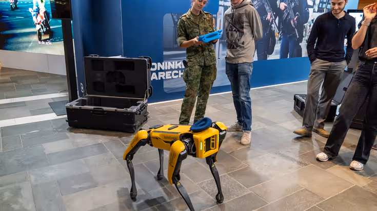 Bezoekers kijken naar een robothond. 