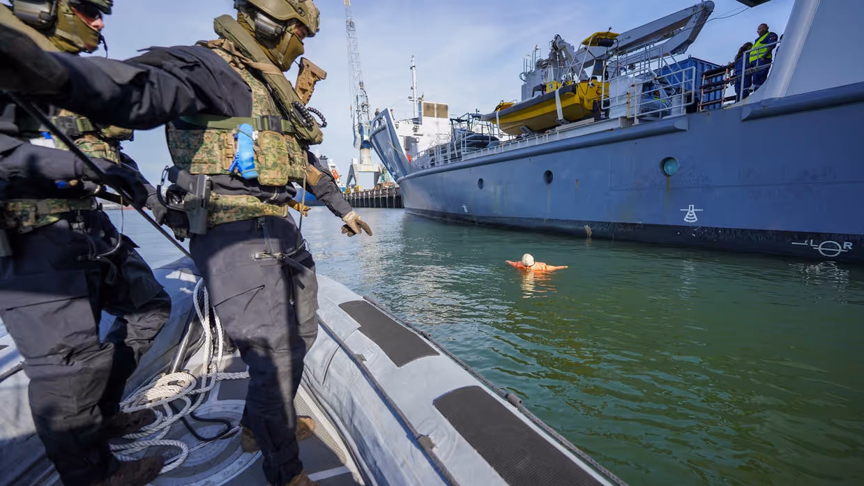 Twee rubberboten kruisen elkaar op het water voor de kade.