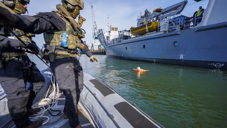 Twee rubberboten kruisen elkaar op het water voor de kade.