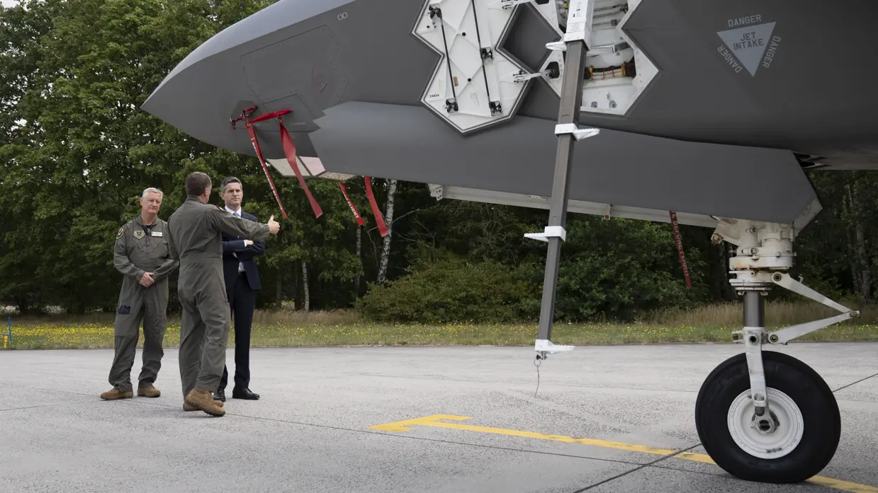 Berendsen op een platform vlak voor een F-35, waarvan het onderstel van de voorkant in beeld is. Een militair in vliegeroveral geeft uitleg. Naast Berendsen staat Commandant Air Combat Command commodore Marcel ‘Bo’ van Egmond.