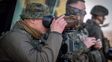 Een Nederlandse militair tuurt door een kijker.