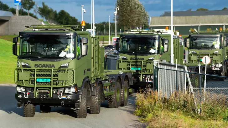 Nieuwe 8-wielaangedreven (4-assig) Scania's Gryphus in de high operational-uitvoering arriveren in een rij bij een kazerne.