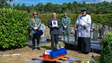 De aalmoezenier leidt de herbegrafenis.