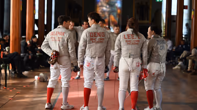 Een groepje schermers pratend met elkaar op een rode loper.