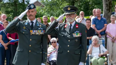 Militairen brengen de eregroet bij het graf.