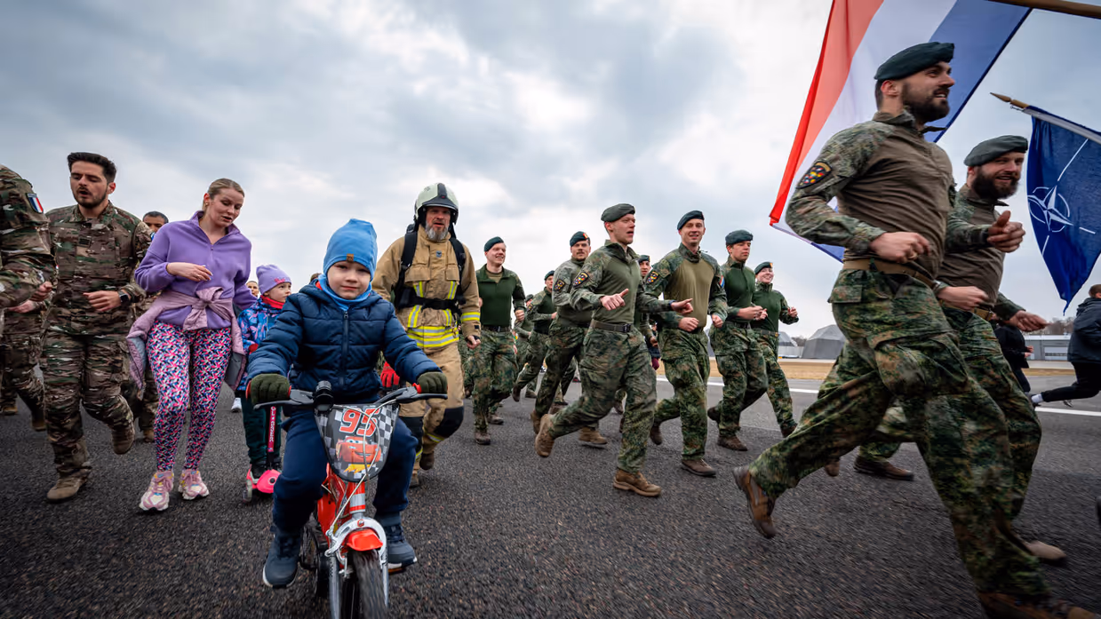 Militairen en burgers rennen over een landingsbaan. 