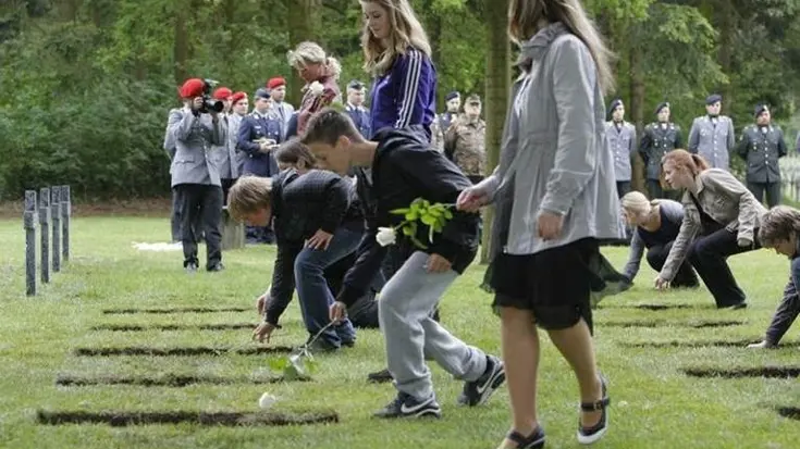 Jongeren leggen rozen op de Begraafplaats voor Duitse Gesneuvelden in Ysselsteyn.