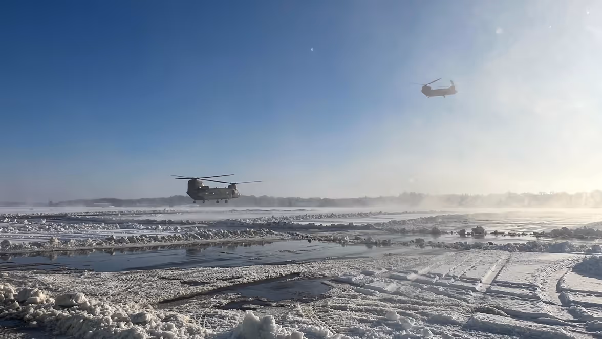 Twee Chinooks boven een besneeuwd platform.