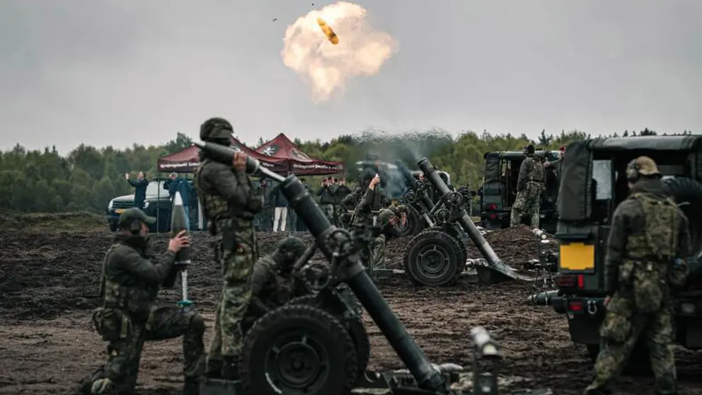 Een rookwolk in de lucht en enkele 120mm mortieren en militairen er omheen.