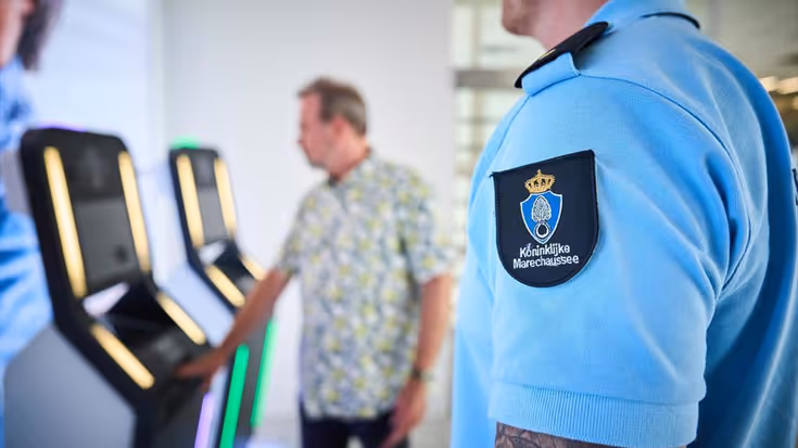 Een Marechaussee kijkt toe hoe een reiziger z’n document inscant bij een machine