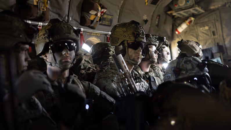 Parachutisten zitten met volledige gevechtsuitrusting in een C-130 Hercules tijdens de vlucht naar de dropzone voor een airborne-operatie.