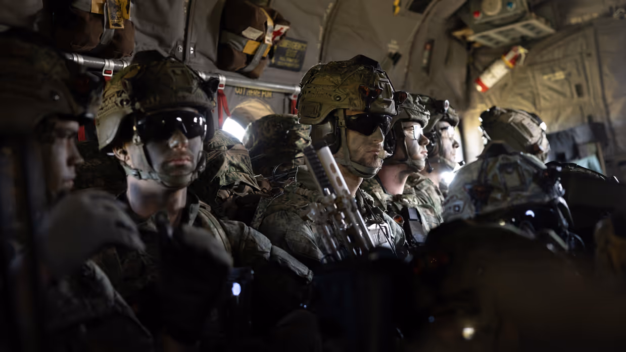 Parachutisten zitten met volledige gevechtsuitrusting in een C-130 Hercules tijdens de vlucht naar de dropzone voor een airborne-operatie.
