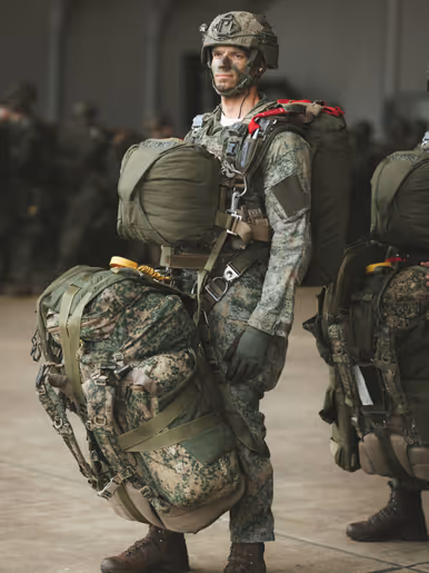 Een parachutist van 11 Luchtmobiele Brigade staat met volledige spronguitrusting en zware bepakking gereed voorafgaand aan een airborne-operatie tijdens oefening Versatile Guard.