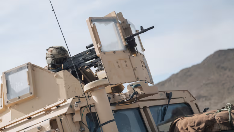 Een schutter kijkt door zijn vizier bovenop een voertuig. 