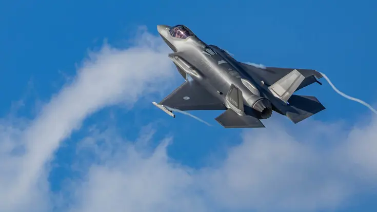 Een F-35-gevechtsvliegtuig vliegt door een strakblauwe lucht.
