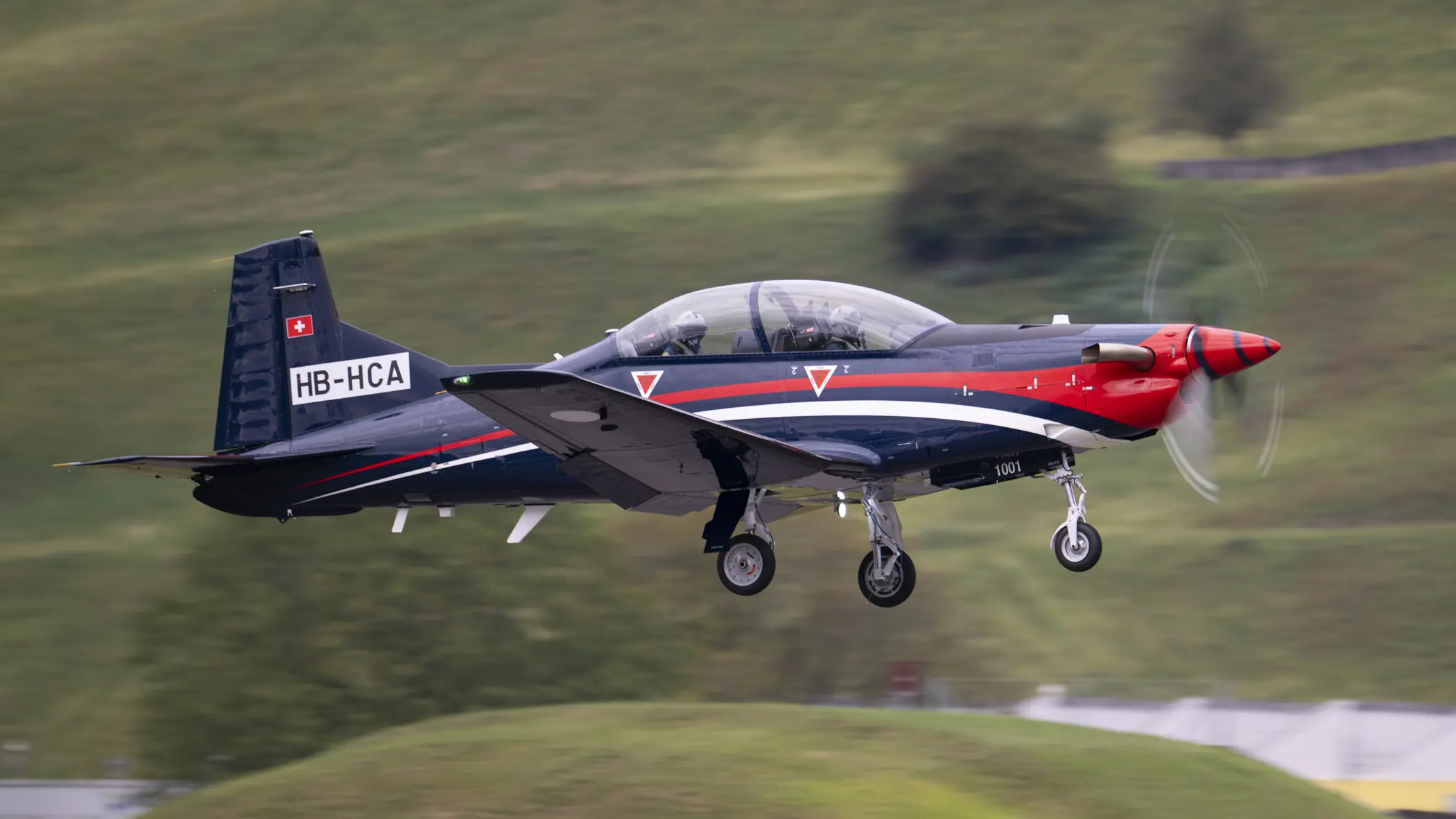 De PC-7 MKX vliegt boven voor een groene achtergrond.