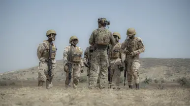 Een Nederlandse militair met korte mouwen geeft uitleg aan 5 Afrikaanse collega’s, die hem omringen