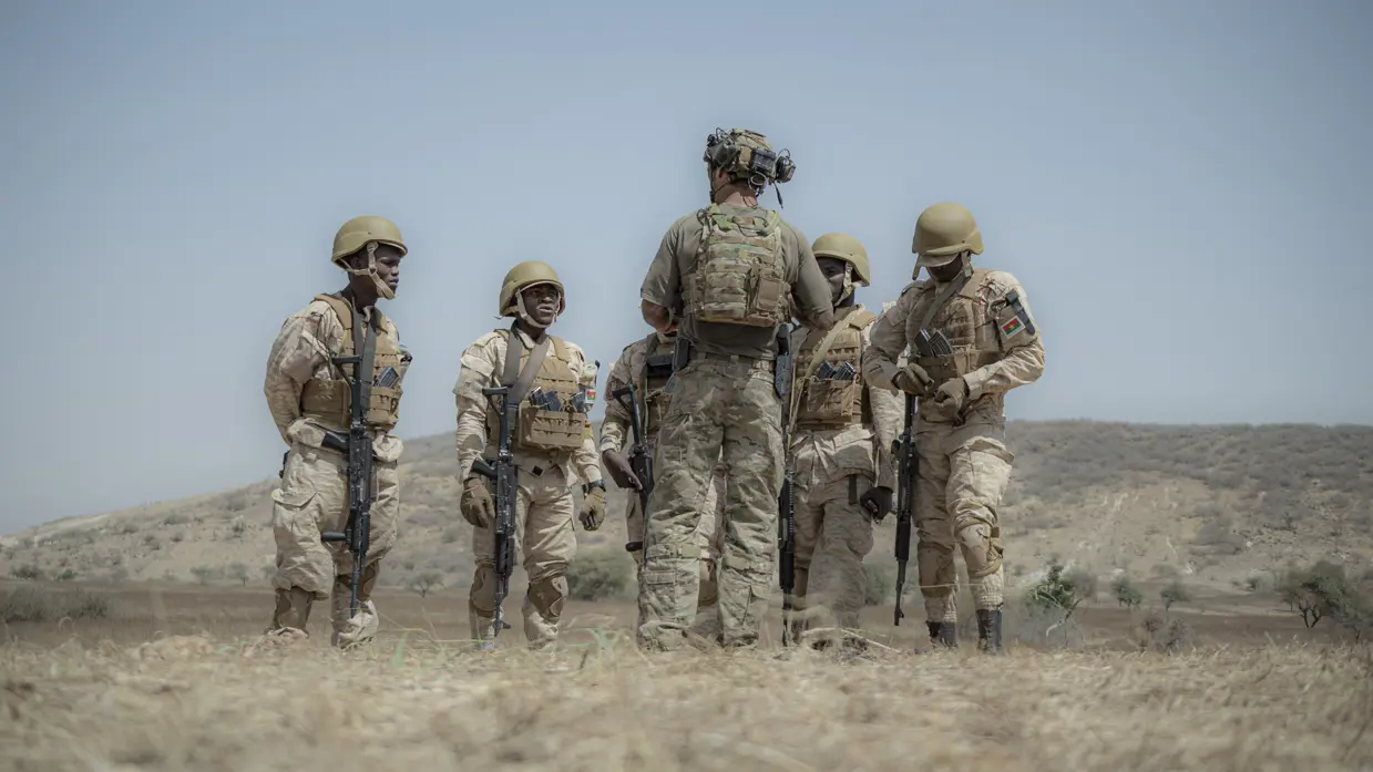 Een Nederlandse militair met korte mouwen geeft uitleg aan 5 Afrikaanse collega’s, die hem omringen