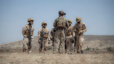 Een Nederlandse militair met korte mouwen geeft uitleg aan 5 Afrikaanse collega’s, die hem omringen