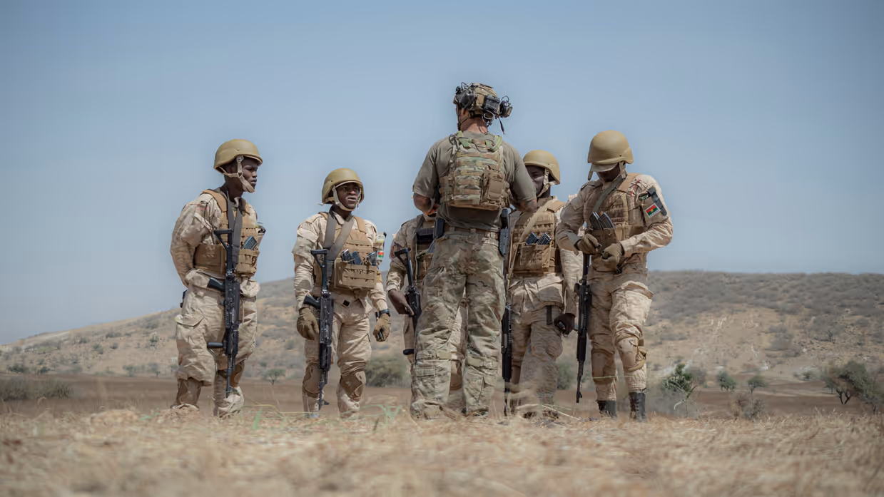 Een Nederlandse militair met korte mouwen geeft uitleg aan 5 Afrikaanse collega’s, die hem omringen