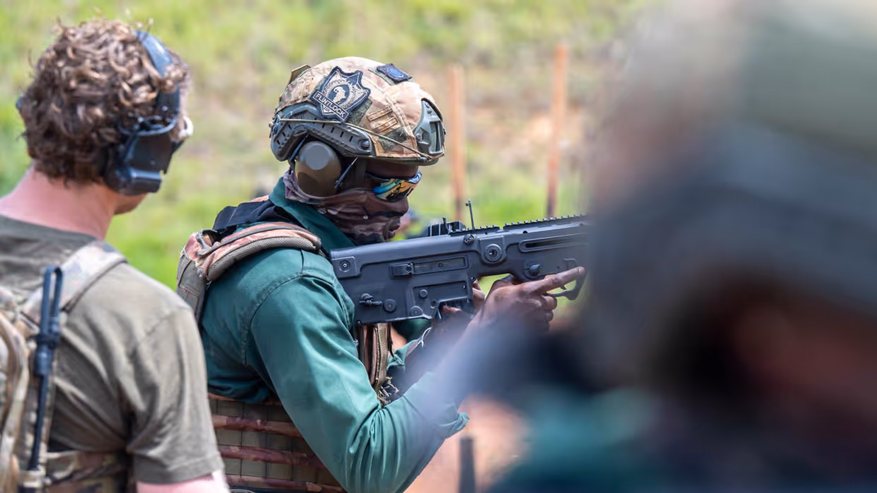Een schietende Afrikaanse militair. Een Nederlandse collega kijkt over zijn schouder mee.
