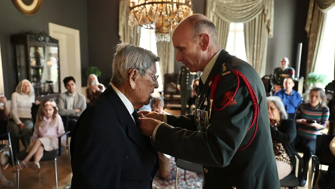 Een veteraan krijgt een ereteken uitgereikt.