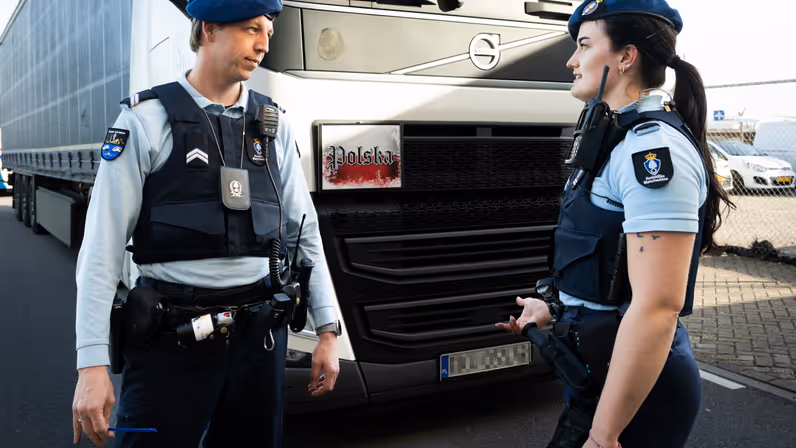 Twee marechaussees voor een vrachtwagen.