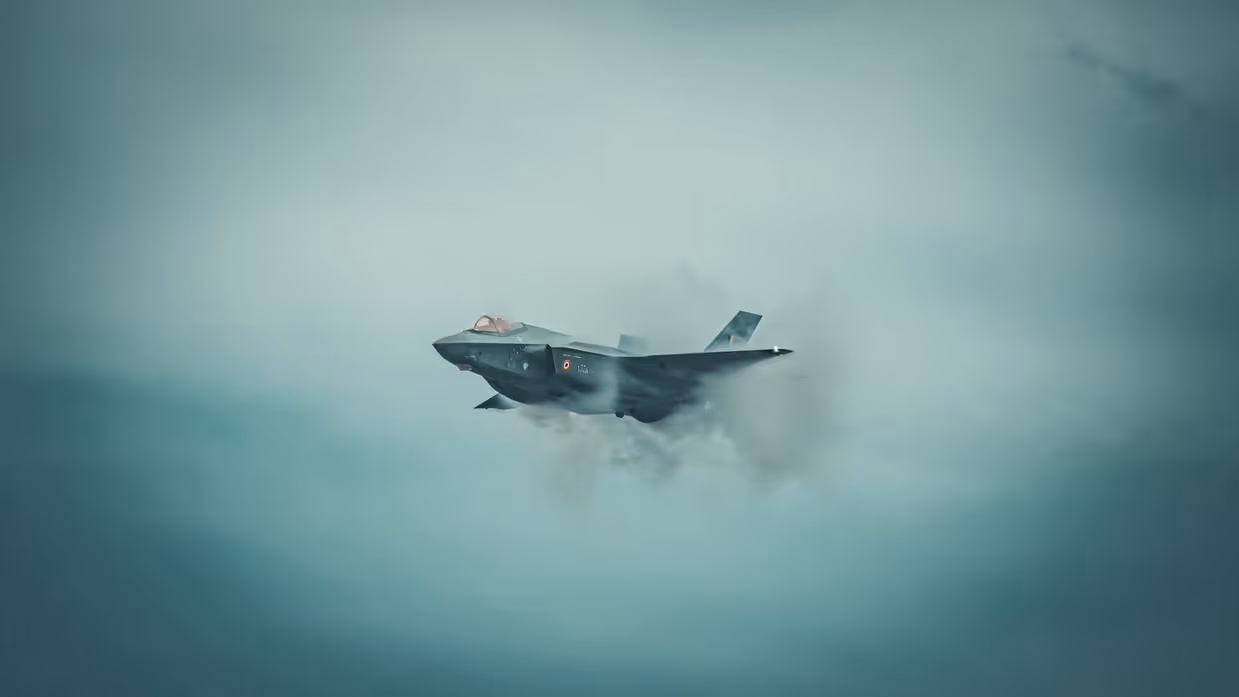 een Belgische F-35 in de lucht met om het toestel een condenswolk. 