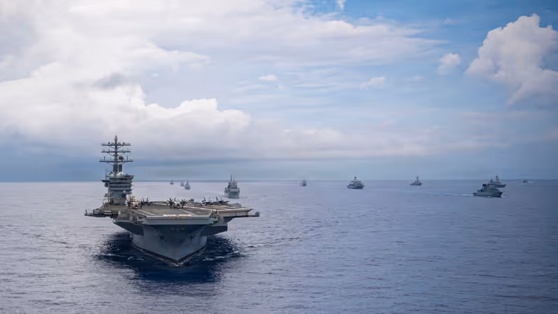 Het vliegdekschip USS Nimitz op zee, met daarachter enkele andere marineschepen.