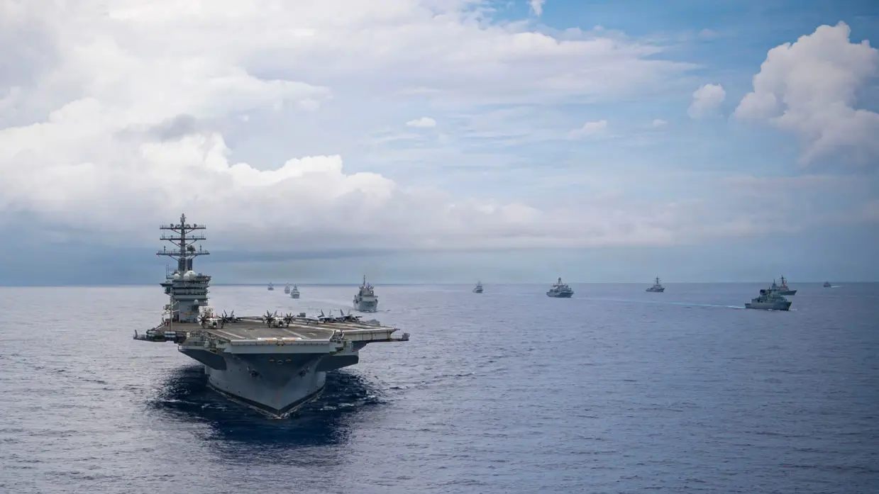 Het vliegdekschip USS Nimitz op zee, met daarachter enkele andere marineschepen.
