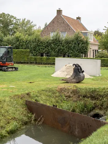 zicht op een sloot, waarin een keerwand is geplaatst.