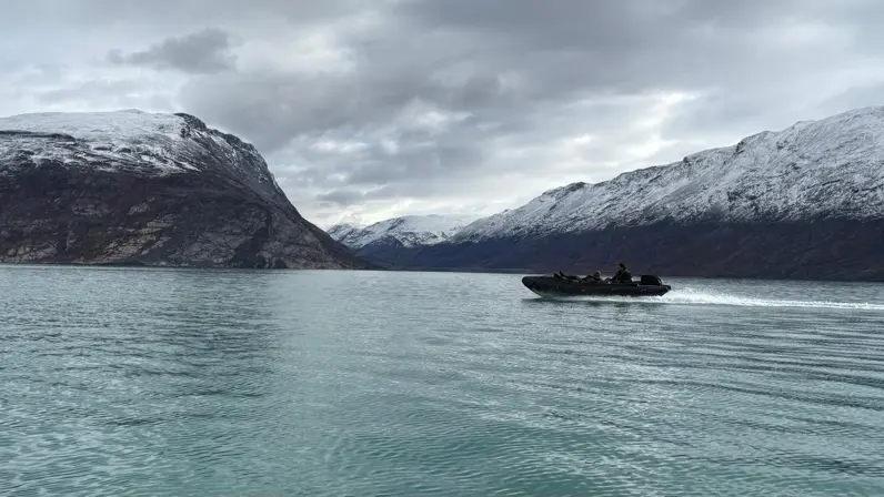 Een rubberboot varend door een weids fjord. 