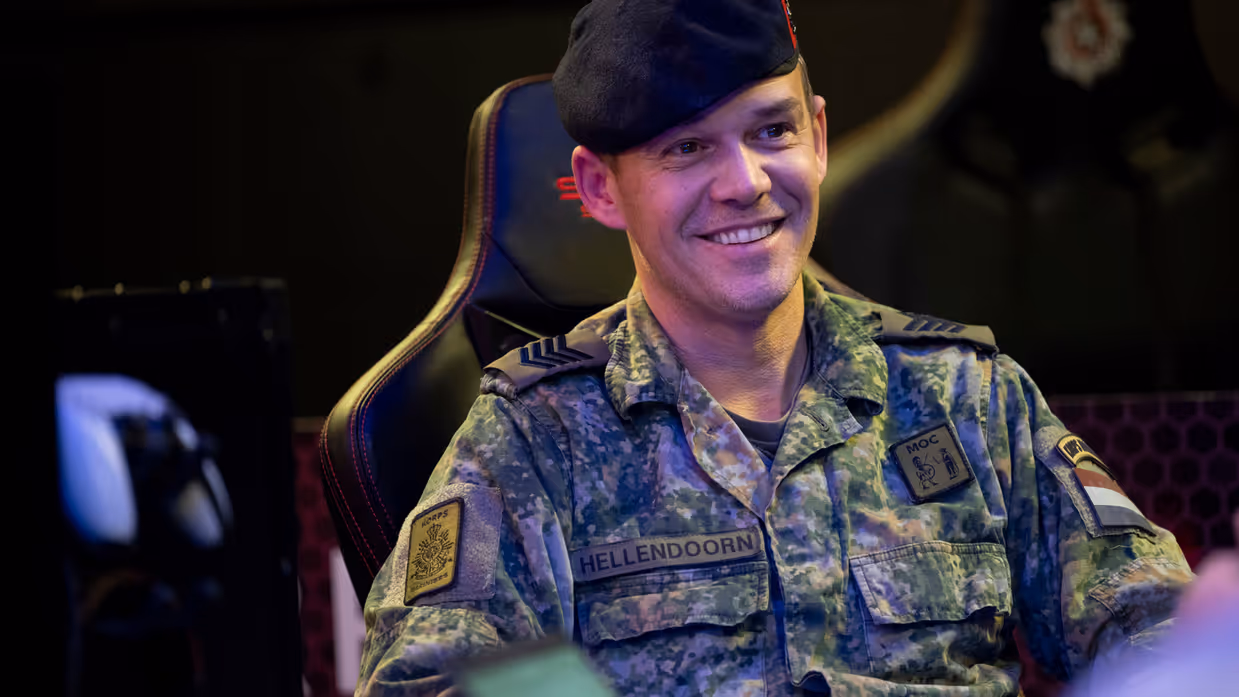 Een lachende sergeant-majoor van de mariniers Michael Hellendoorn zittend in de game room. 