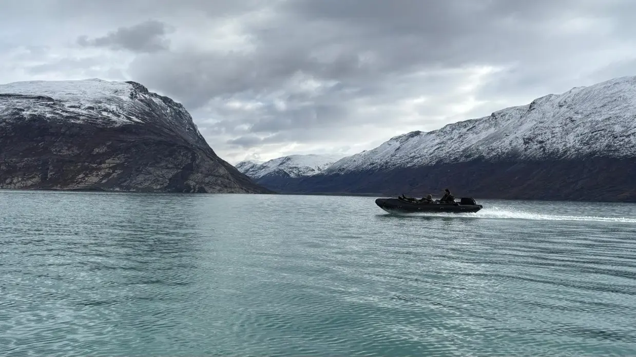 Een rubberboot varend door een weids fjord. 