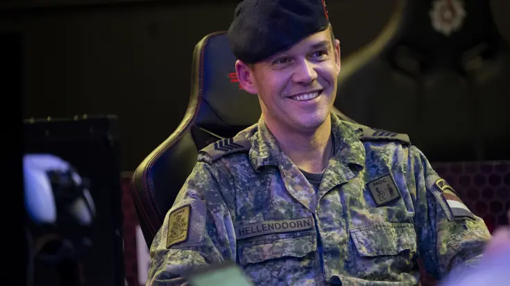 Een lachende sergeant-majoor van de mariniers Michael Hellendoorn zittend in de game room. 