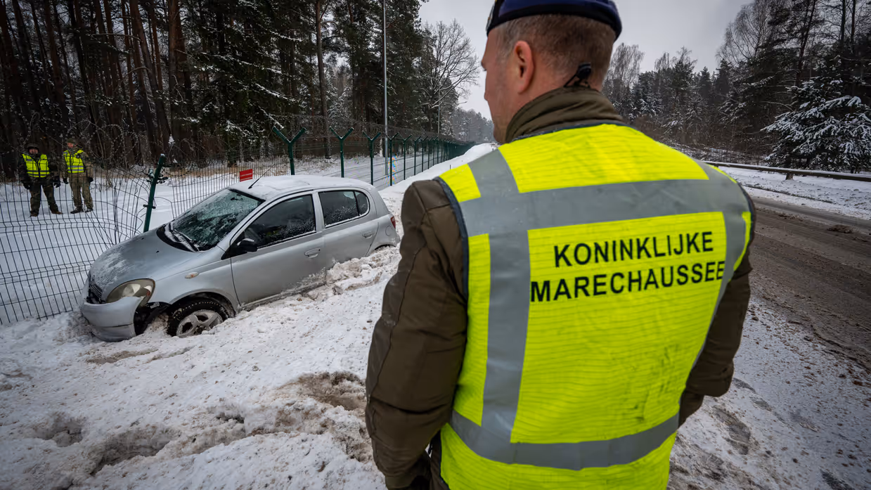 een marechaussee die kijkt naar een van de weg geraakte auto.  