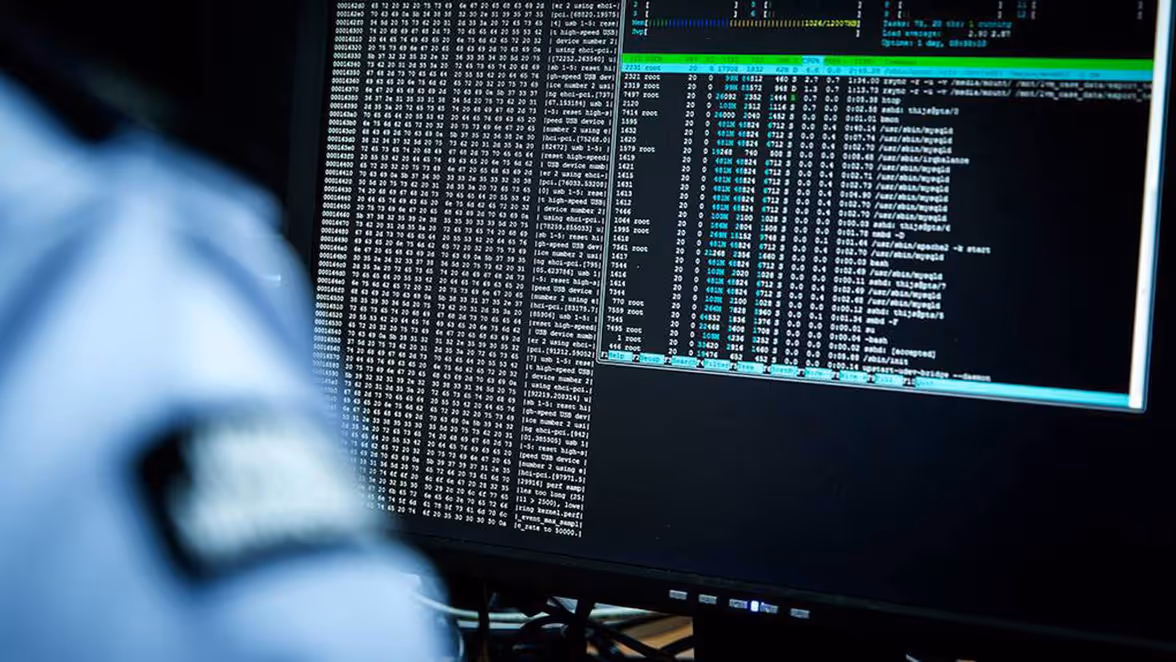 Een beeldscherm met in de hoek een marechaussee. 