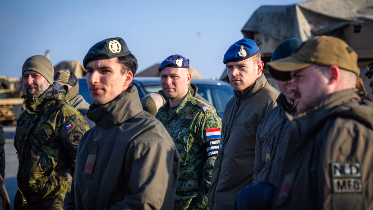 Meerdere militairen die allen dezelfde kant uit kijken.  