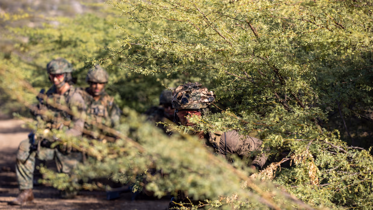 Een geknielde marinier op oefenterrein Wacawa met zijn geweer in de aanslag.     