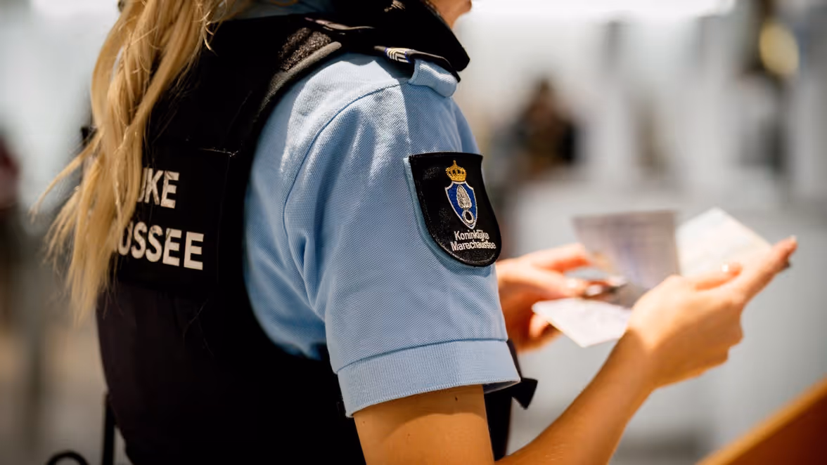 Een marechaussee controleert een document.