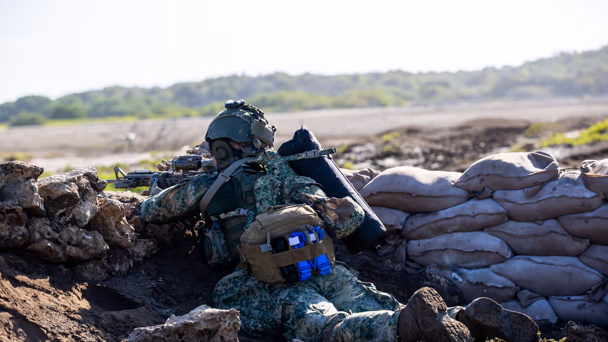 een liggende zeesoldaat, die van achter een borstwering met zijn geweer schiet.   