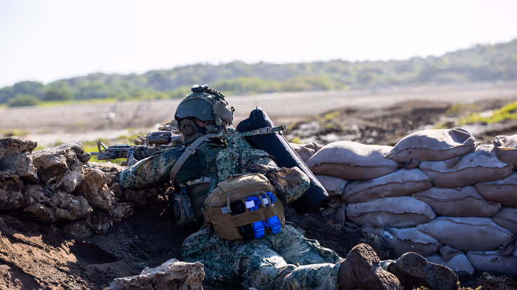 een liggende zeesoldaat, die van achter een borstwering met zijn geweer schiet.   