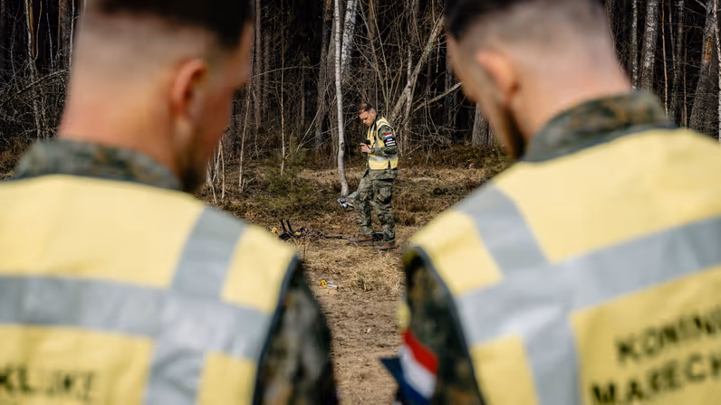 twee marechaussees die een brancard een ziekenauto in duwen. 