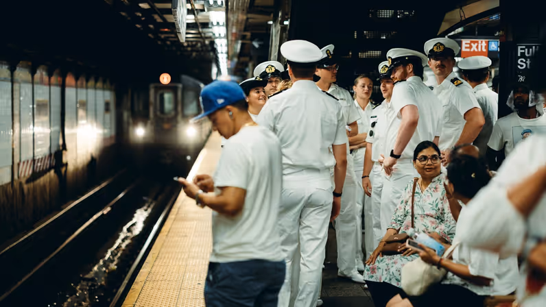 Marinepersoneel wacht op het perron samen met New Yorkers, terwijl de metro eraan kom. 