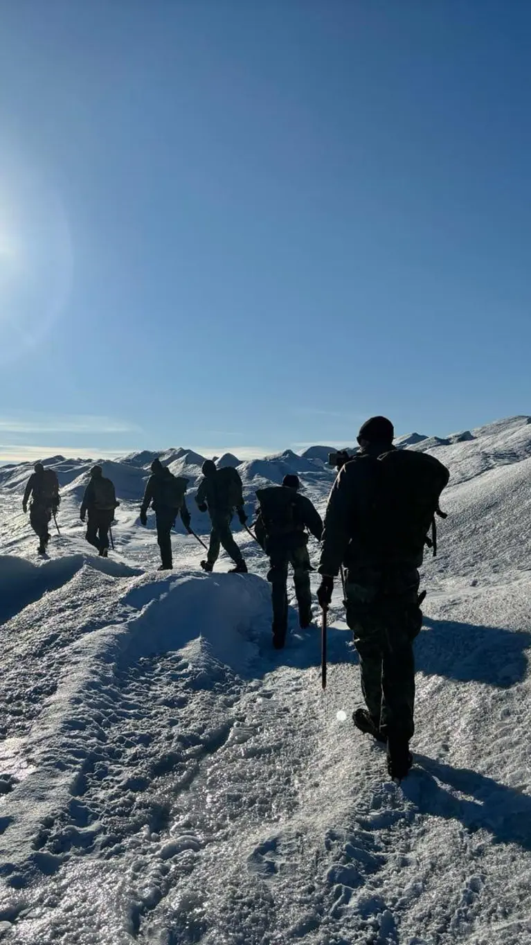 mariniers achter elkaar lopend in een weids wit landschap. 