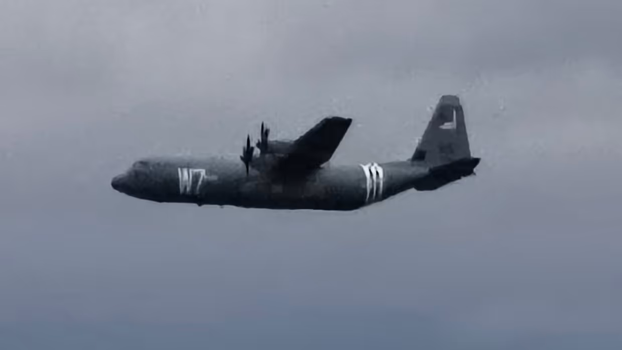 een C130 Hercules voorzien van geallieerde herkenningsstrepen tegen een donkere achtergrond.