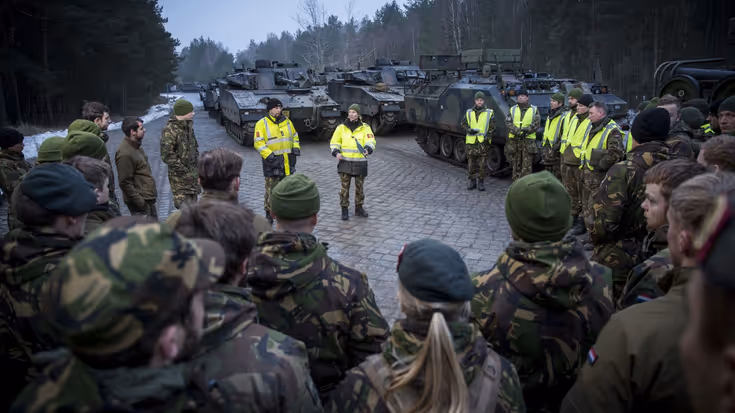Militairen buiten luisteren naar collega's die uitleg geven over verplaatsing.