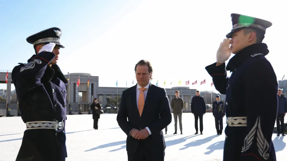 Staatssecretaris Tuinman staat tussen 2 saluerende Zuid-Koreaanse militairen. 