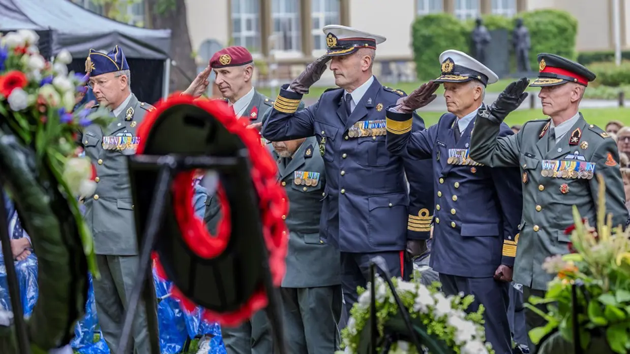Militairen salueren bij de kransen tijdens de herdenking